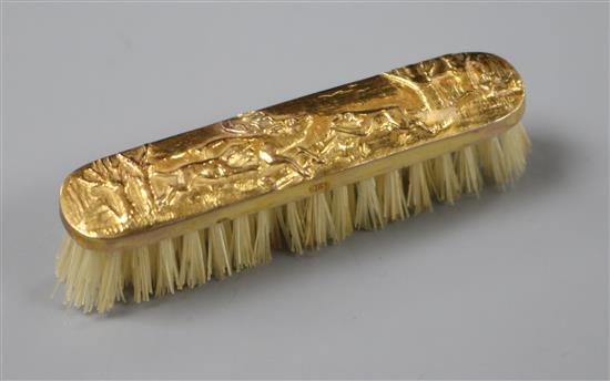 An early 20th century repousse 9ct gold mounted miniature brush, with hunting scene, in leather case, 6cm.